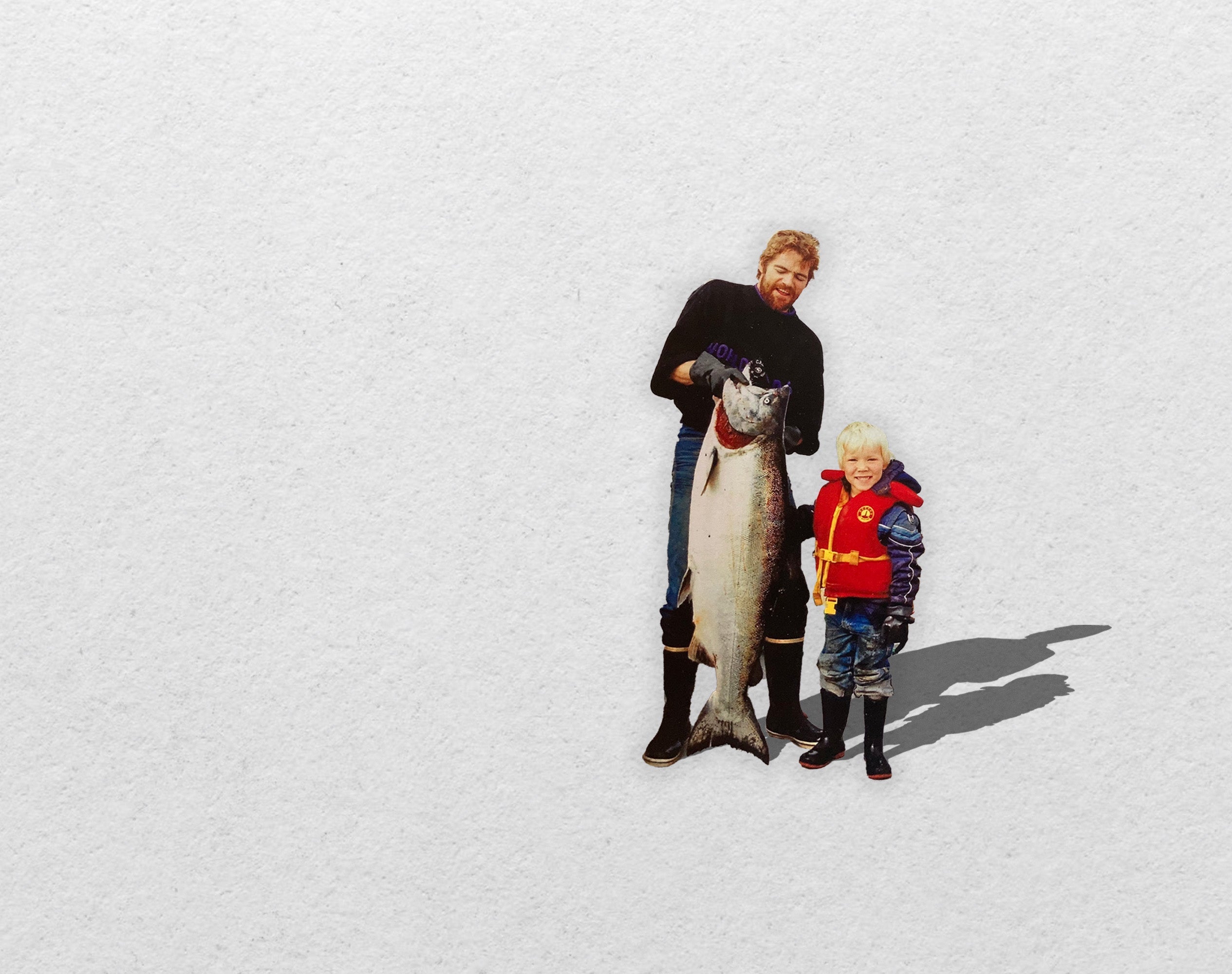 An old photo shows Don Cameron holding a large salmon next to his young son Ryan, who wears a red life jacket.