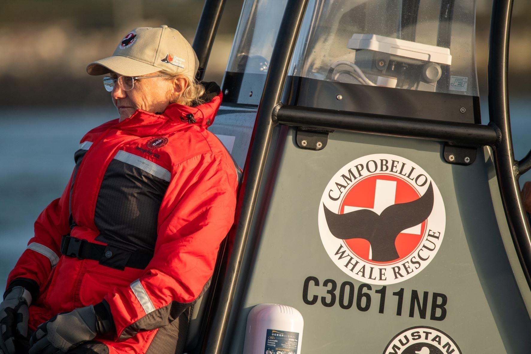 Senior Scientist Moira Brown wearing protective red Mustang Survival flotation clothing sits aboard a Campobello Whale Rescue boat.