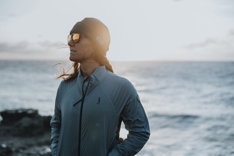 A profile view shows Emily Nagel wearing mirrored sunglasses and a Torrens jacket while looking out at a bright ocean.