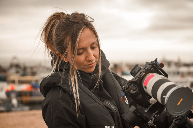 Professional photographer, Alice Callow, preparing her camera gear for a shoot on the water, wearing the Atlas 190 life jacket